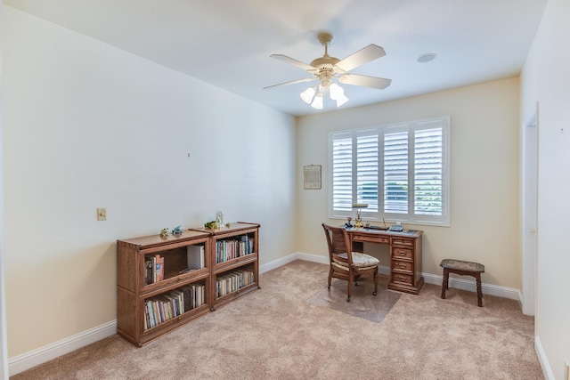 office area featuring light carpet, a ceiling fan, and baseboards