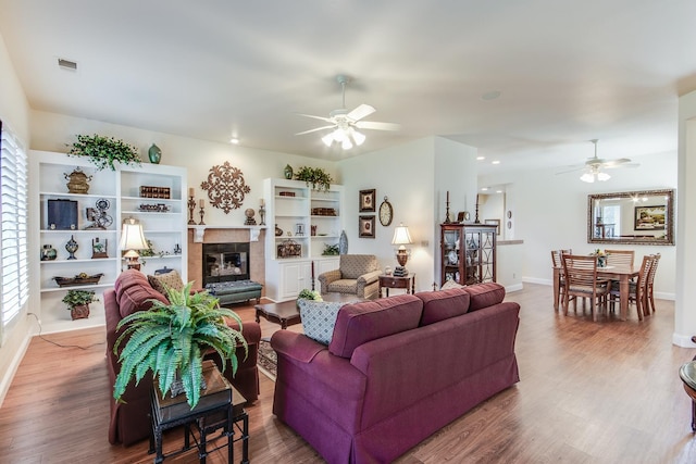 living room with ceiling fan, a tile fireplace, wood finished floors, baseboards, and recessed lighting