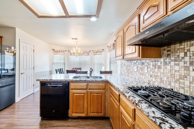 6371 N Babigian Ave, Fresno, CA 93722 - kitchen with under cabinet range hood, black appliances, a sink, a peninsula, and a chandelier