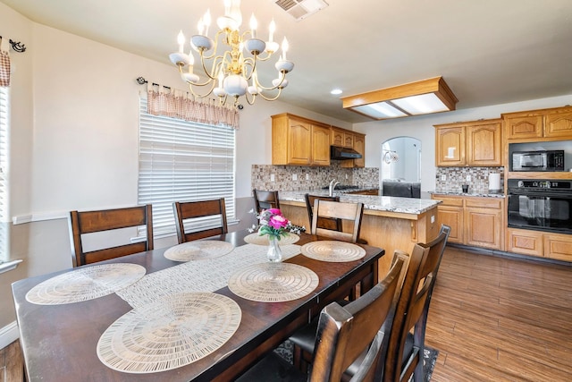 6371 N Babigian Ave, Fresno, CA 93722 - dining space with a chandelier, dark wood-style flooring, and arched walkways