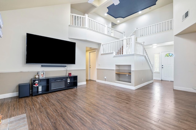 6371 N Babigian Ave, Fresno, CA 93722 - unfurnished living room featuring a high ceiling, stairway, baseboards, and wood finished floors