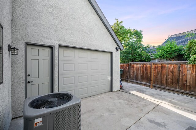 525 E Shelldrake Cir, Fresno, CA 93730 - garage at dusk featuring concrete driveway and central AC unit