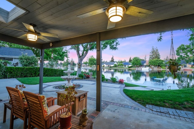 525 E Shelldrake Cir, Fresno, CA 93730 - patio terrace at dusk featuring ceiling fan, a patio area, a water view, and a lawn