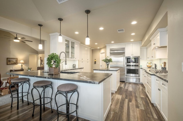 525 E Shelldrake Cir, Fresno, CA 93730 - kitchen with dark wood-style flooring, tasteful backsplash, ceiling fan, appliances with stainless steel finishes, and a kitchen bar