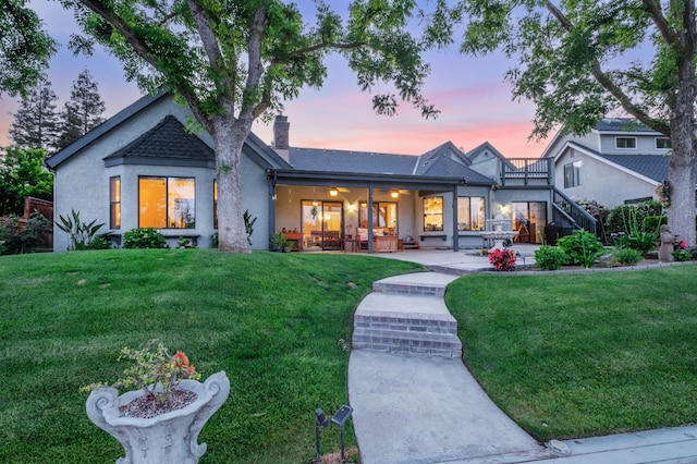 525 E Shelldrake Cir, Fresno, CA 93730 - rear view of house with a lawn, a chimney, stucco siding, and stairway