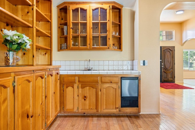 37086 Marciel Ave, Madera, CA 93636 - kitchen featuring arched walkways, a sink, tile counters, light wood finished floors, and brown cabinets