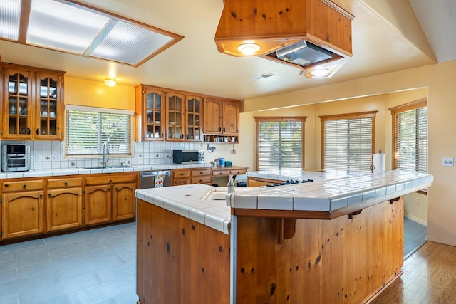37086 Marciel Ave, Madera, CA 93636 - kitchen featuring a sink, appliances with stainless steel finishes, brown cabinetry, tasteful backsplash, and a kitchen breakfast bar