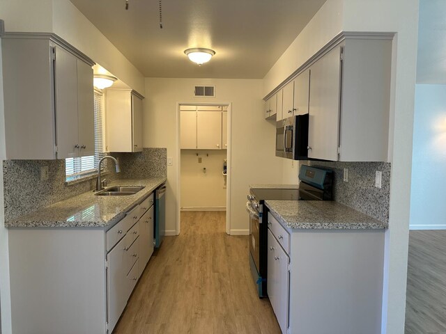 1658 E Paul Ave, Fresno, CA 93710 - kitchen featuring appliances with stainless steel finishes, a sink, decorative backsplash, light wood-style flooring, and baseboards