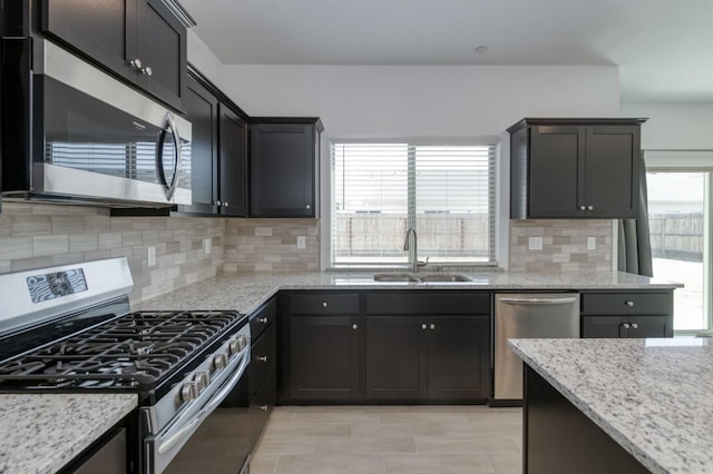 2613 W Mallard, Hanford, CA 93230 - kitchen with appliances with stainless steel finishes, a sink, light stone countertops, and tasteful backsplash