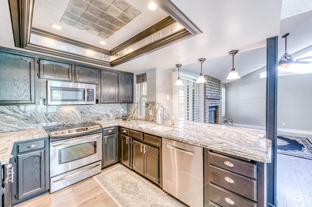 6211 N Cleo Ave, Fresno, CA 93722 - kitchen with appliances with stainless steel finishes, a sink, a tray ceiling, a peninsula, and light wood-style floors