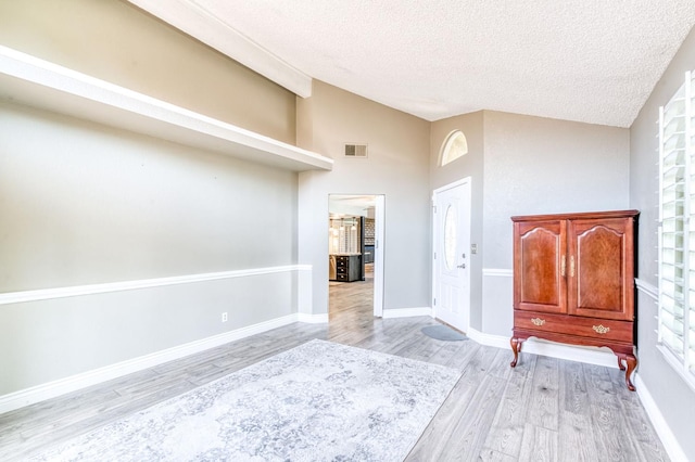 6211 N Cleo Ave, Fresno, CA 93722 - foyer featuring vaulted ceiling, light wood finished floors, a textured ceiling, and baseboards
