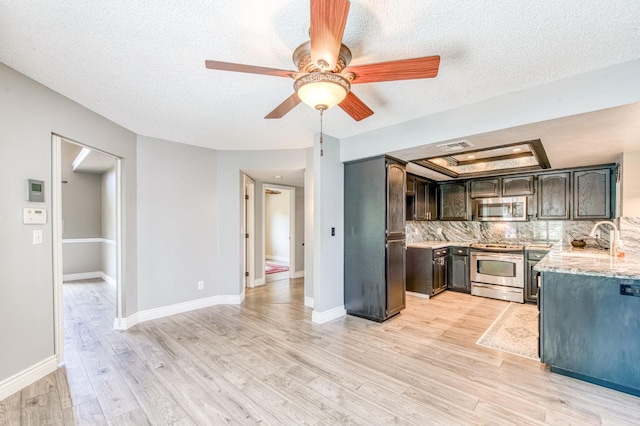 6211 N Cleo Ave, Fresno, CA 93722 - kitchen featuring stainless steel appliances, a textured ceiling, light wood-type flooring, ceiling fan, and a tray ceiling