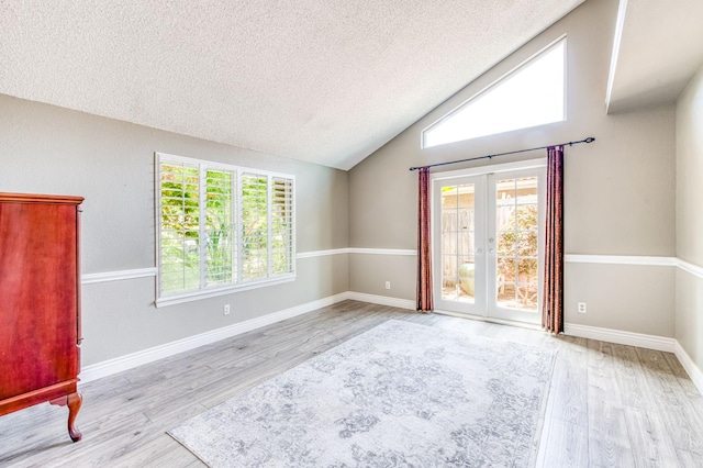 6211 N Cleo Ave, Fresno, CA 93722 - spare room featuring a textured ceiling, wood finished floors, lofted ceiling, and french doors
