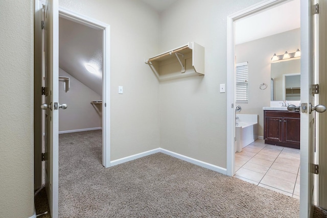 spacious closet featuring light carpet, a sink, and lofted ceiling