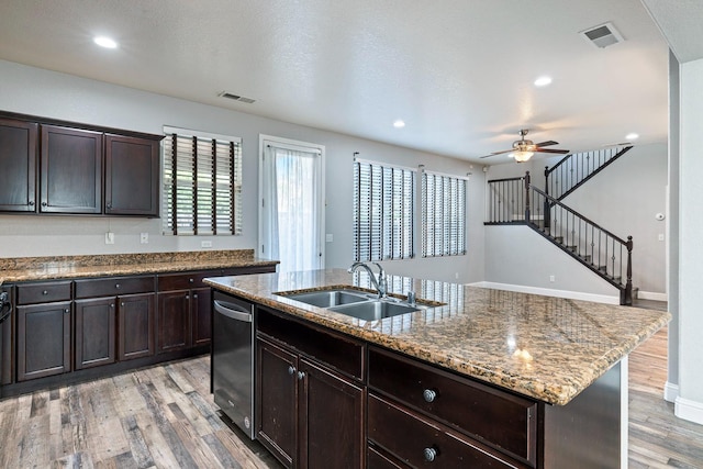 kitchen featuring a sink, dishwasher, light wood-style floors, a ceiling fan, and light stone countertops