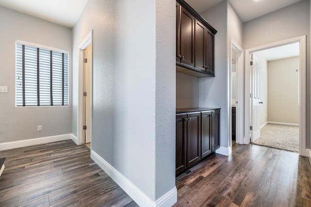 hallway with dark wood-type flooring and baseboards