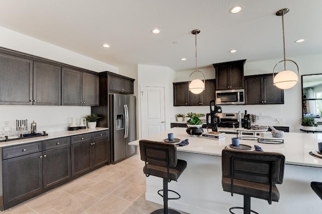 1173 Maclure Ave W, Madera, CA 93636 - kitchen featuring appliances with stainless steel finishes, light countertops, a breakfast bar, decorative light fixtures, and recessed lighting