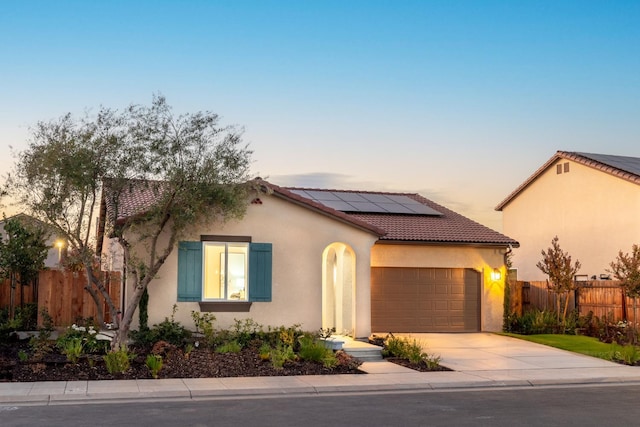 1173 Maclure Ave W, Madera, CA 93636 - mediterranean / spanish home featuring roof mounted solar panels, an attached garage, concrete driveway, stucco siding, and fence