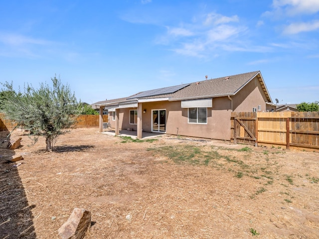 1585 Dallas St, Dinuba, CA 93618 - back of house featuring stucco siding, a fenced backyard, a patio area, roof mounted solar panels, and a gate