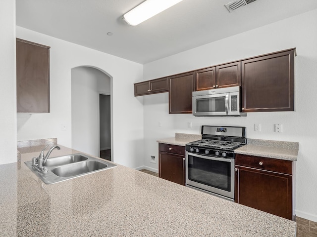 1585 Dallas St, Dinuba, CA 93618 - kitchen with stainless steel appliances, a sink, arched walkways, dark brown cabinets, and light countertops