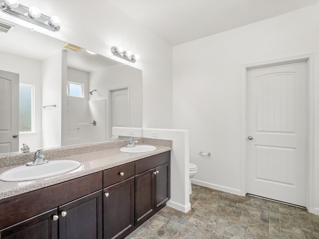 1585 Dallas St, Dinuba, CA 93618 - full bath featuring toilet, a shower, double vanity, baseboards, and stone finish floors