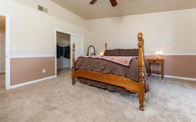 carpeted bedroom featuring a closet, ceiling fan, baseboards, and a walk in closet