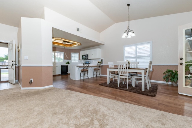 carpeted dining area with vaulted ceiling, a chandelier, and baseboards