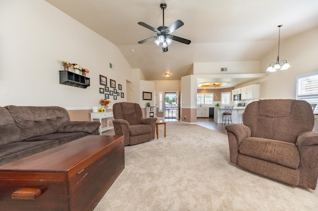 living room featuring light colored carpet, a ceiling fan, healthy amount of natural light, a chandelier, and high vaulted ceiling