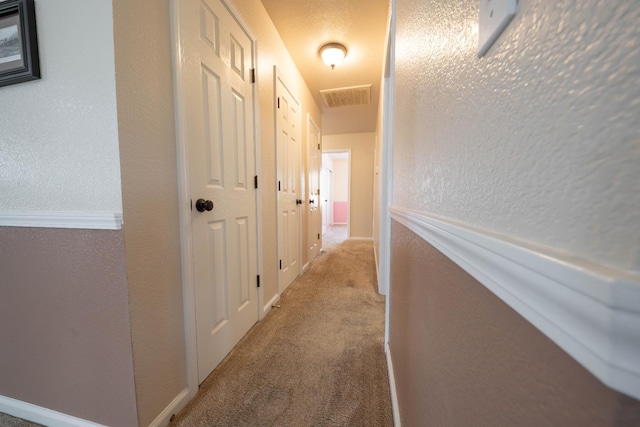 hall with carpet and a textured wall