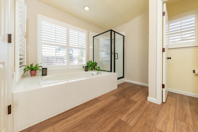 bathroom with wood finished floors, a garden tub, and a stall shower