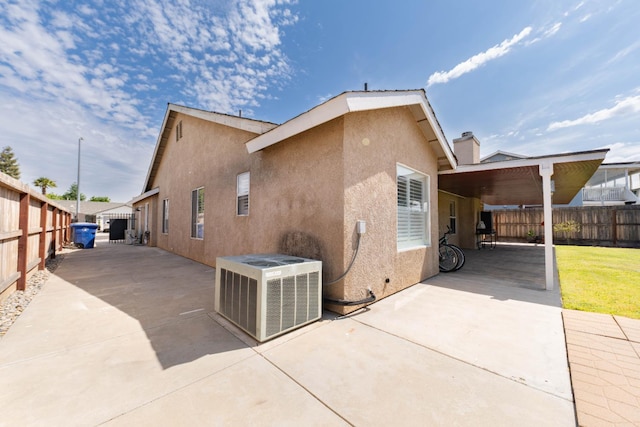 view of side of home featuring central AC unit, a fenced backyard, and stucco siding