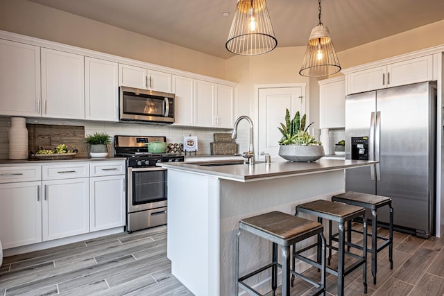 1161 Maclure Ave W, Madera, CA 93636 - kitchen featuring appliances with stainless steel finishes, a sink, wood tiled floors, white cabinets, and tasteful backsplash