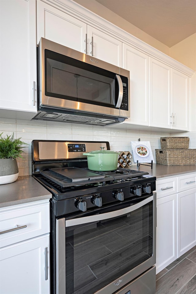 1161 Maclure Ave W, Madera, CA 93636 - kitchen with stainless steel appliances, white cabinets, tasteful backsplash, and dark wood-type flooring