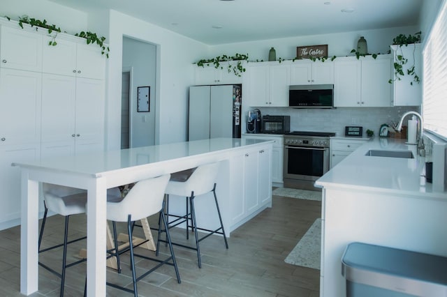 324 Sunset Dr S, Madera, CA 93636 - kitchen with appliances with stainless steel finishes, a sink, white cabinets, backsplash, and light wood-style flooring