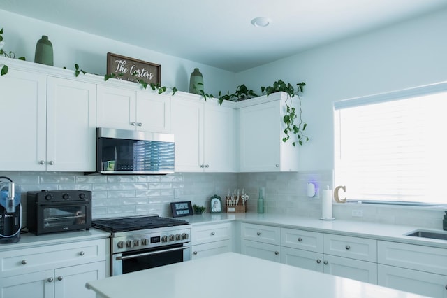 324 Sunset Dr S, Madera, CA 93636 - kitchen with stainless steel appliances, light countertops, backsplash, and white cabinetry