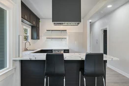 705 Poplar, Fresno, CA 93728 - kitchen with a sink, a peninsula, a kitchen bar, baseboards, and light wood-style flooring