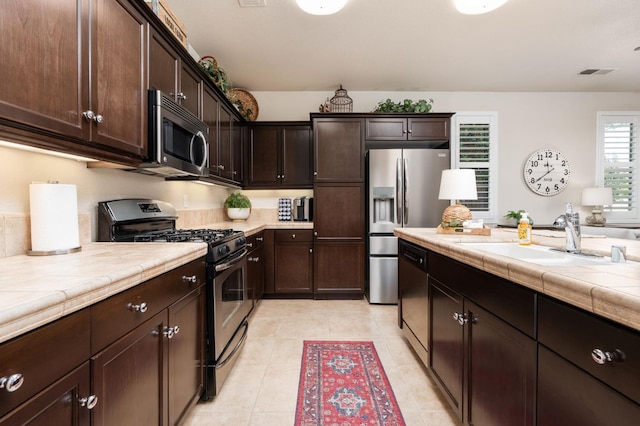 3942 Harlan Ranch Blvd, Clovis, CA 93619 - kitchen featuring stainless steel appliances, a sink, dark brown cabinets, and tile counters