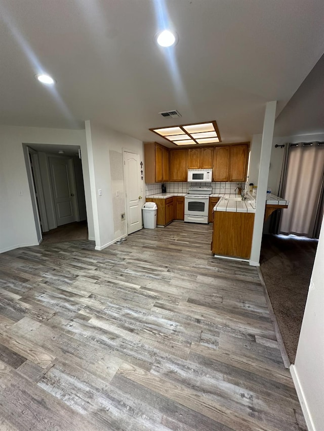5838 W Fallon Ave, Fresno, CA 93722 - kitchen featuring white appliances, brown cabinets, wood finished floors, backsplash, and recessed lighting