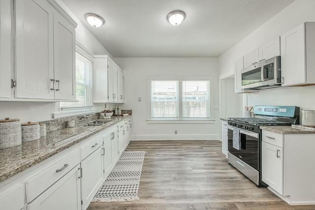 1010 N Ferger Ave, Fresno, CA 93728 - kitchen featuring appliances with stainless steel finishes, a sink, white cabinets, light stone countertops, and light wood finished floors