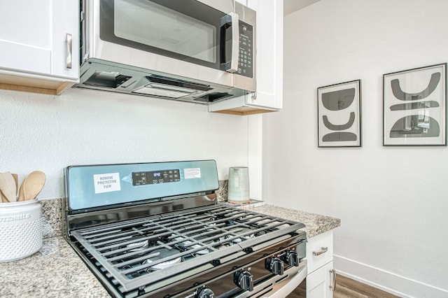 1010 N Ferger Ave, Fresno, CA 93728 - kitchen with appliances with stainless steel finishes, white cabinetry, baseboards, wood finished floors, and light stone countertops