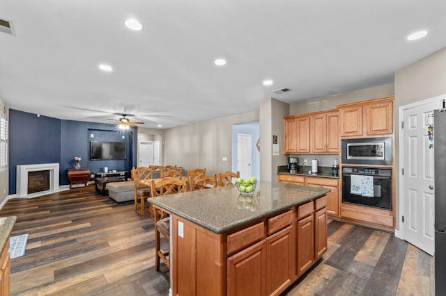 993 Pinewood Ave, Sanger, CA 93657 - kitchen featuring appliances with stainless steel finishes, dark wood-type flooring, a breakfast bar area, a center island, and ceiling fan