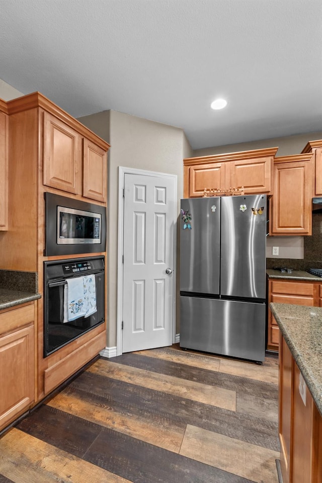 993 Pinewood Ave, Sanger, CA 93657 - kitchen featuring appliances with stainless steel finishes, dark wood-style flooring, recessed lighting, dark stone counters, and under cabinet range hood