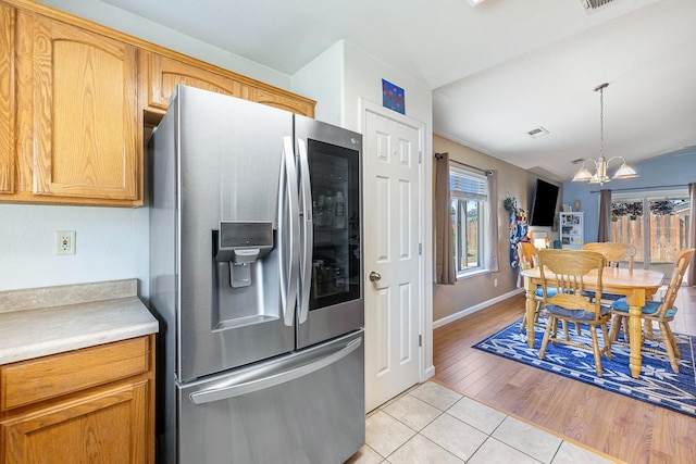 kitchen with stainless steel fridge, a chandelier, light tile patterned floors, light countertops, and decorative light fixtures