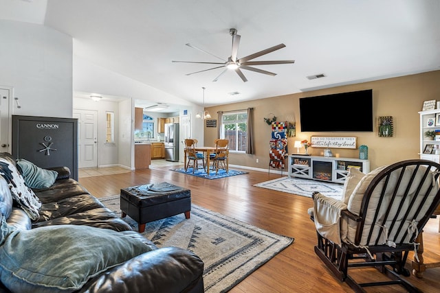 living area with ceiling fan, light wood-style floors, lofted ceiling, and baseboards