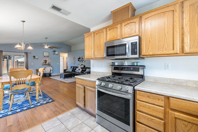 kitchen with appliances with stainless steel finishes, vaulted ceiling, light countertops, ceiling fan, and light tile patterned flooring