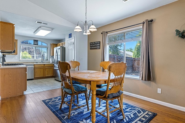 dining room with vaulted ceiling, light wood-style floors, a chandelier, and baseboards