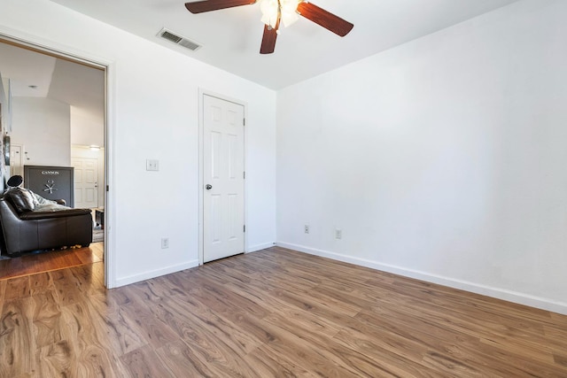 empty room with ceiling fan, wood finished floors, and baseboards