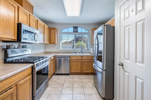 kitchen featuring stainless steel appliances, a sink, light countertops, and light tile patterned floors