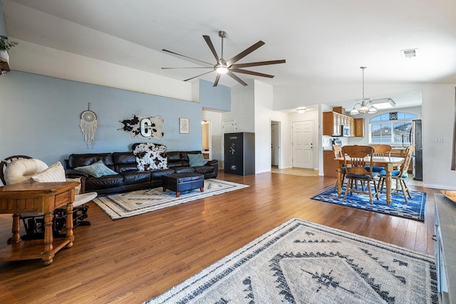 living room with lofted ceiling, ceiling fan, light wood finished floors, and a chandelier