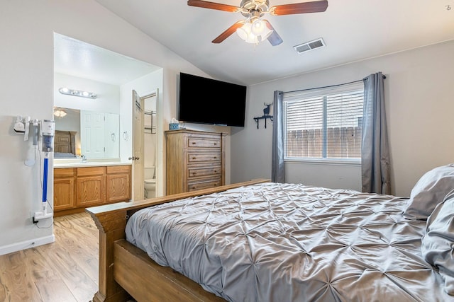 bedroom featuring lofted ceiling, light wood-style floors, ensuite bathroom, and a ceiling fan